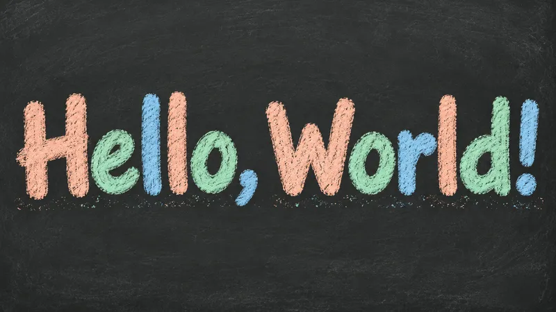 Hello, World! in peach, mint and blue chalk letters on a charcoal chalkboard